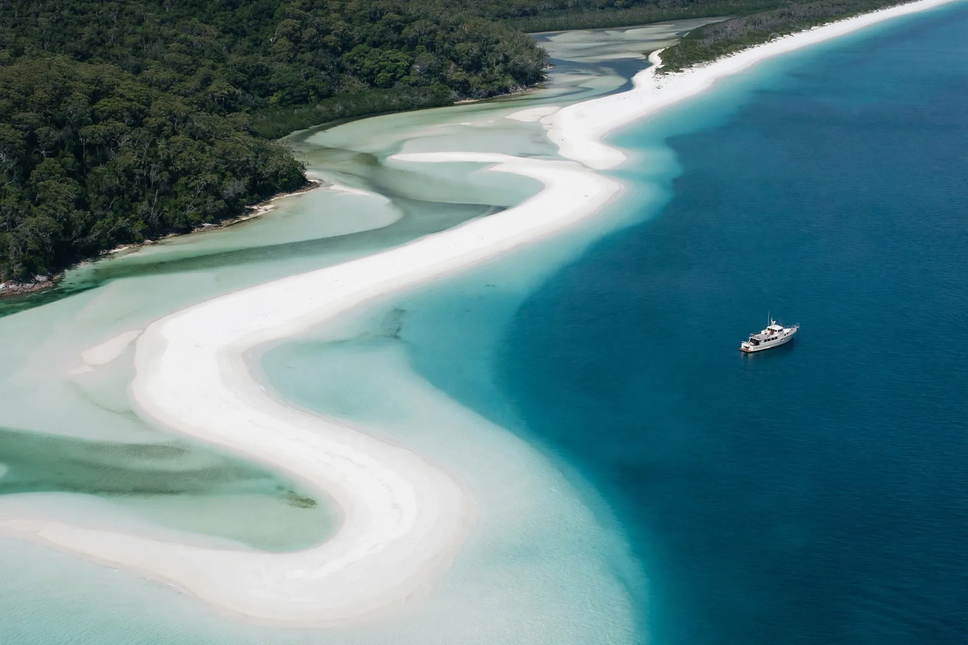 A yacht beside the white sands and turquoise shallows of Hill Inlet, Whitsundays