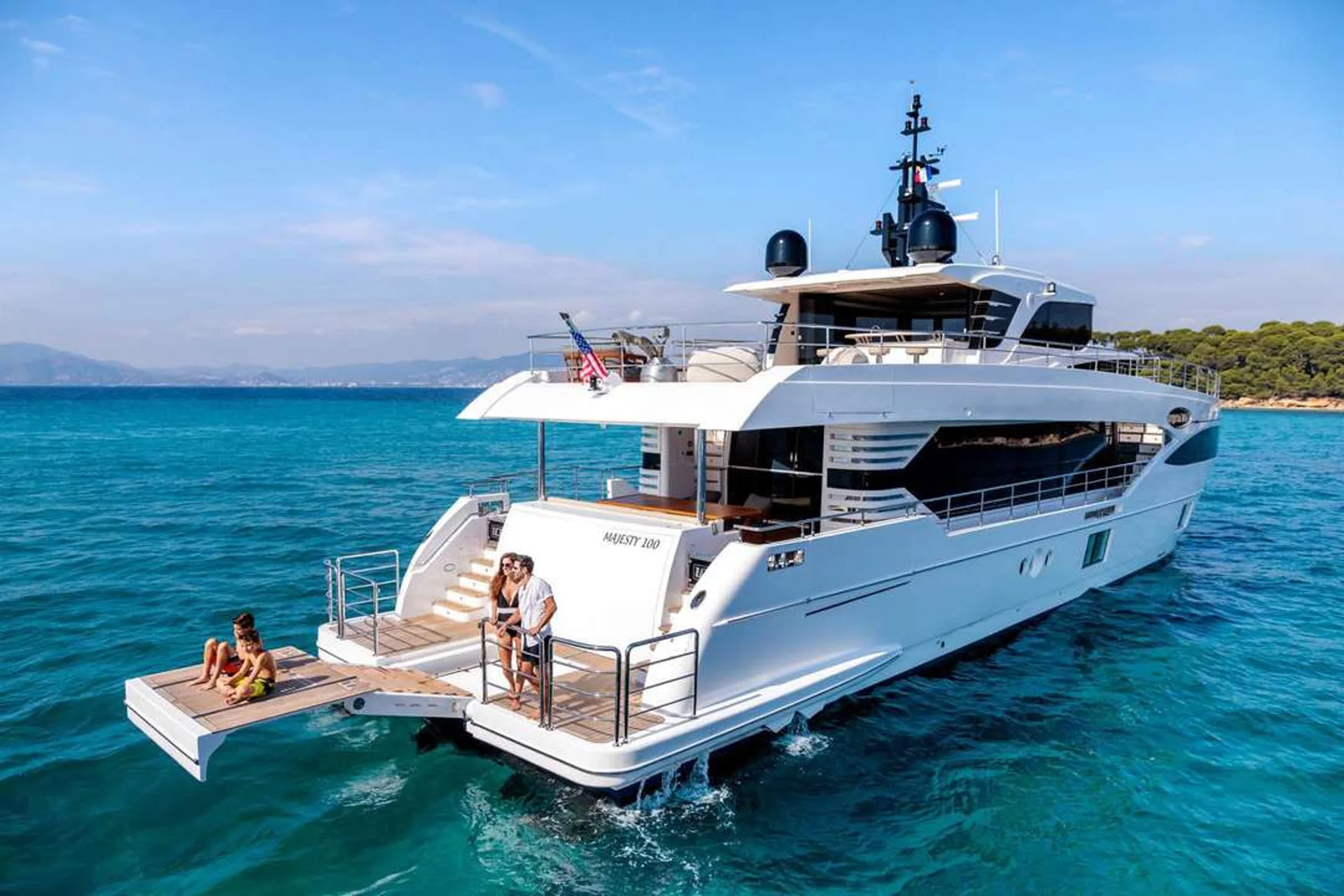 Legacy viewed from aft quarter while anchored in bright blue water.