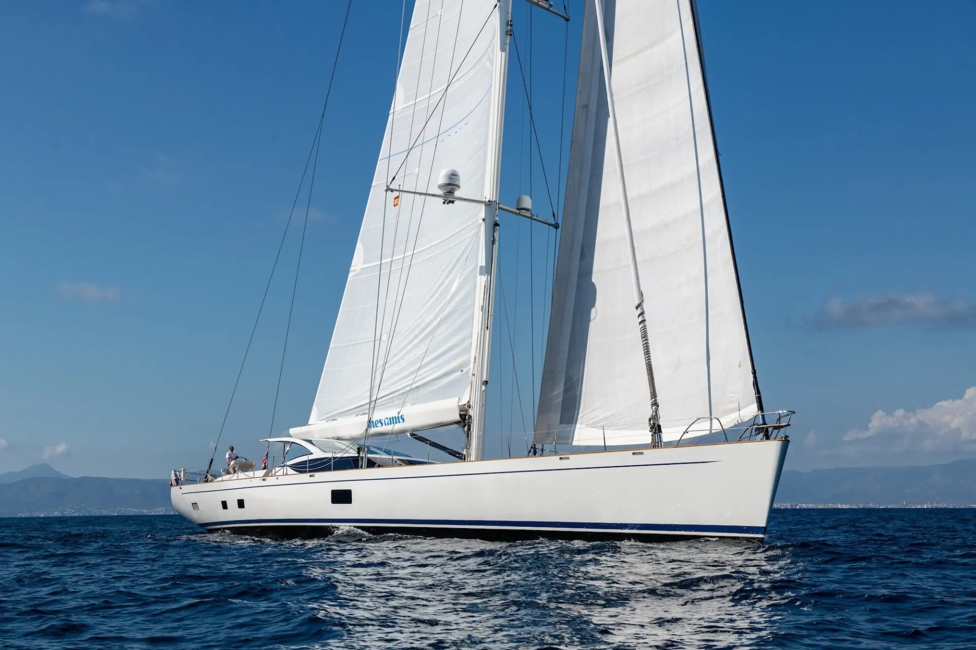 Mes Amis sailing across calm blue water under full sail.
