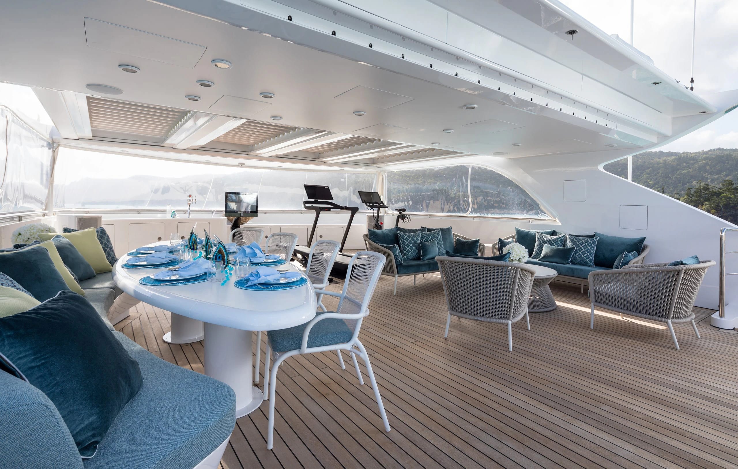 Mischief's aft deck prepared for guests beside a wooded shoreline