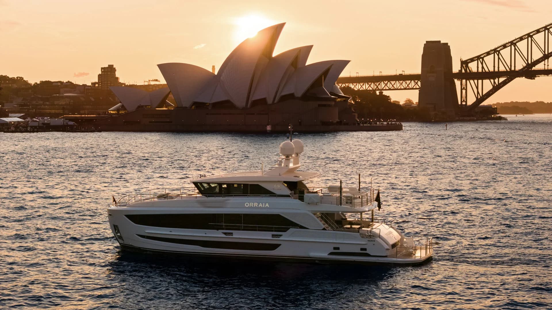 Orraia on Sydney Harbour at sunset with the Opera House and Harbour Bridge behind