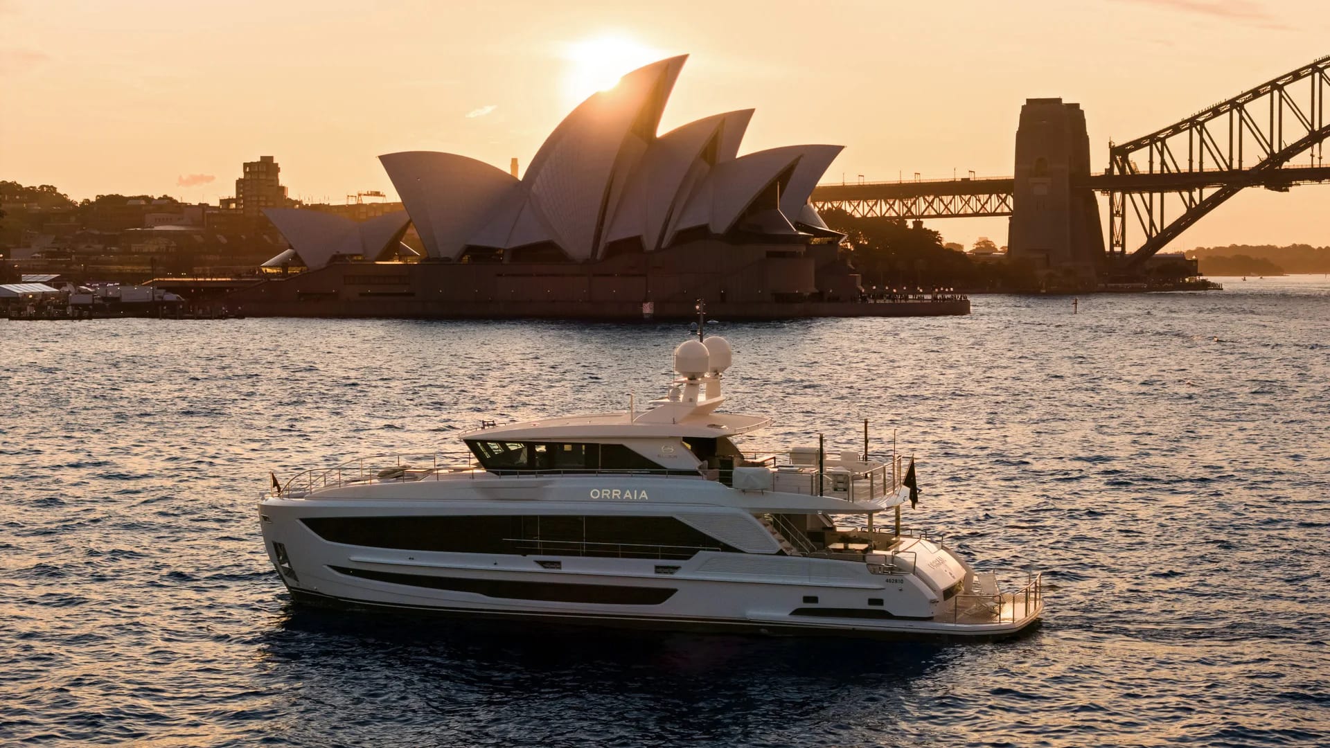 Orraia on Sydney Harbour at sunset with the Opera House and Harbour Bridge behind