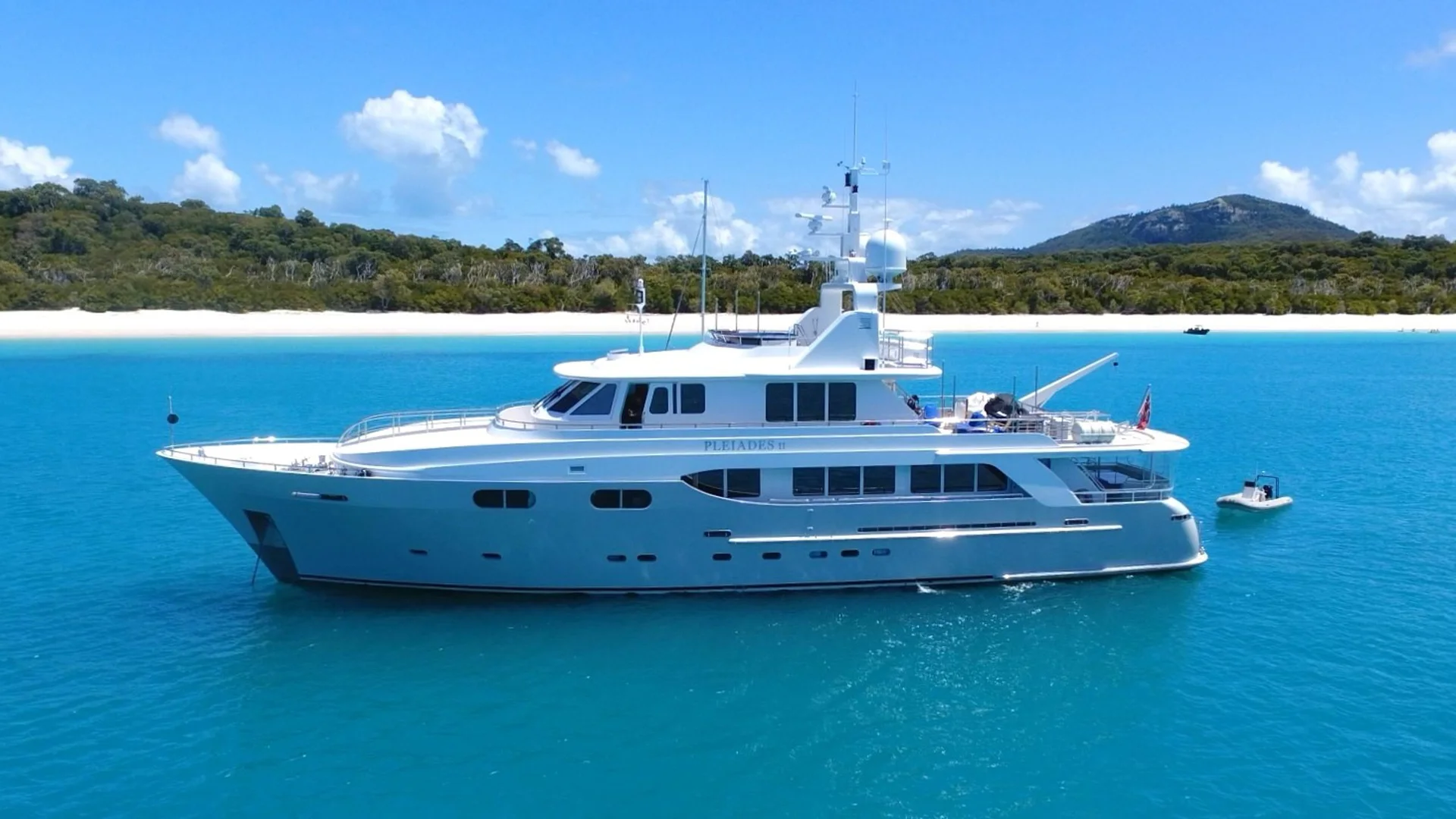 Pleiades II viewed from port side at anchor on turquoise water